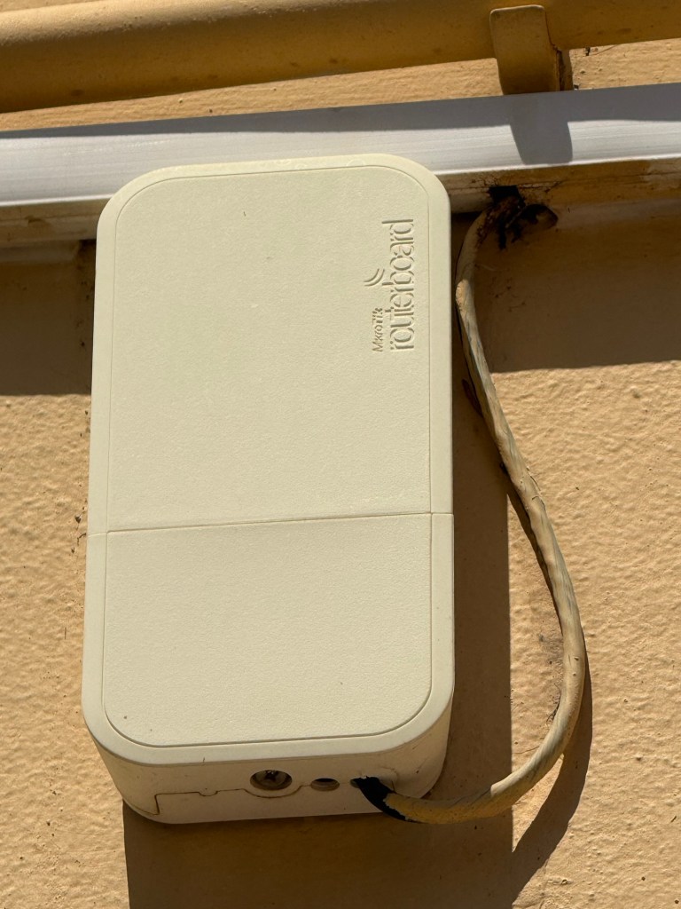 A white routeboard device mounted on a wall with a cable attached.