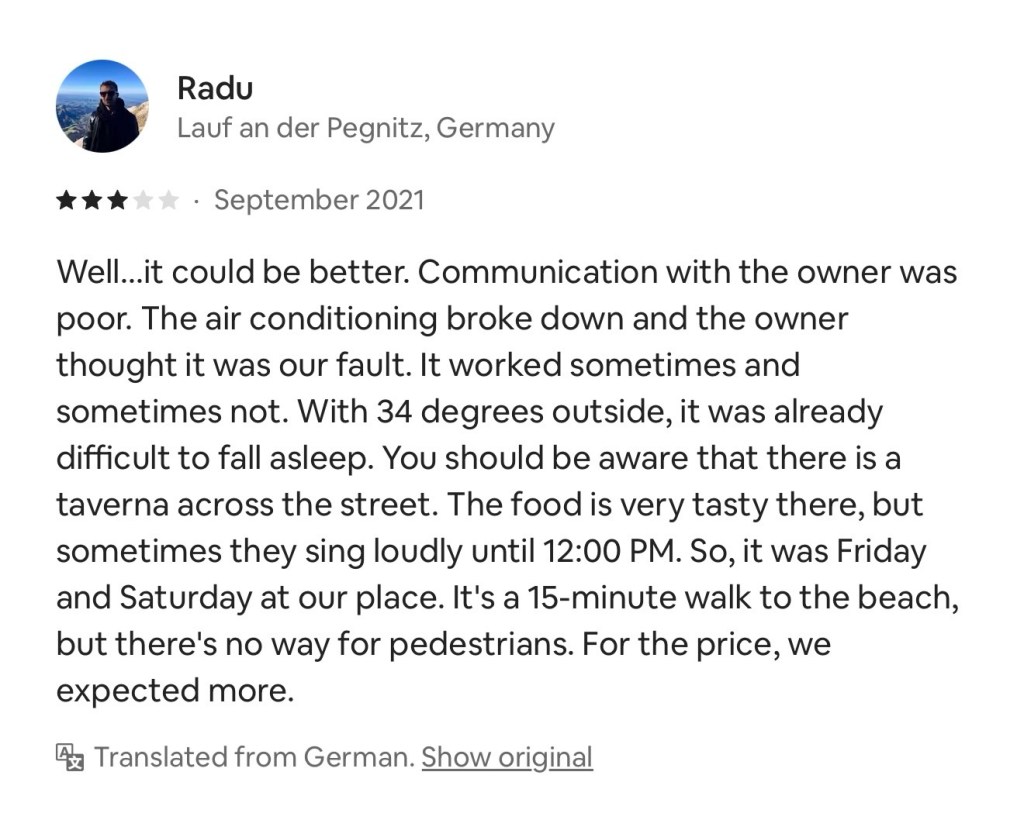 User review mentioning communication issues with the owner, air conditioning problems, and nearby taverna noise. Notes on food quality and accessibility to the beach.